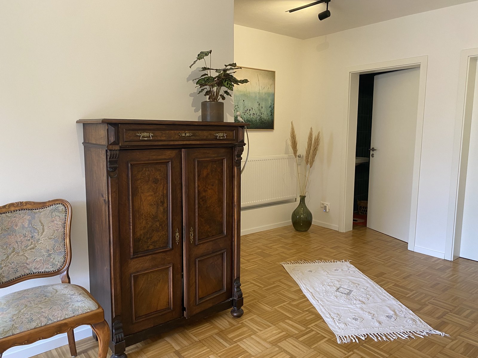 Treatment room with an old wooden cupboard, a plant, pampas grass and a picture on the wall